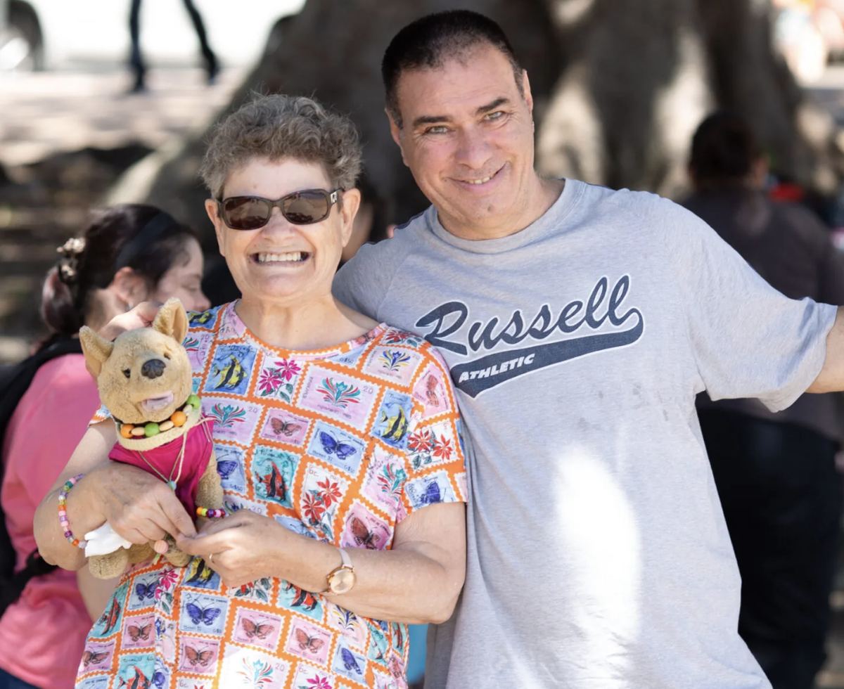 A Therapy Care participant and support worker smiling together outdoors.